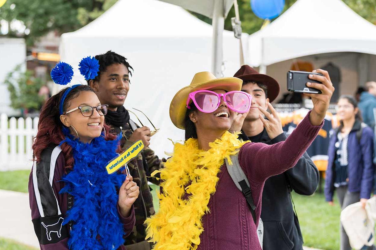 Students wearing costume props taking a selfie at University of Rochester Meliora Weekend.